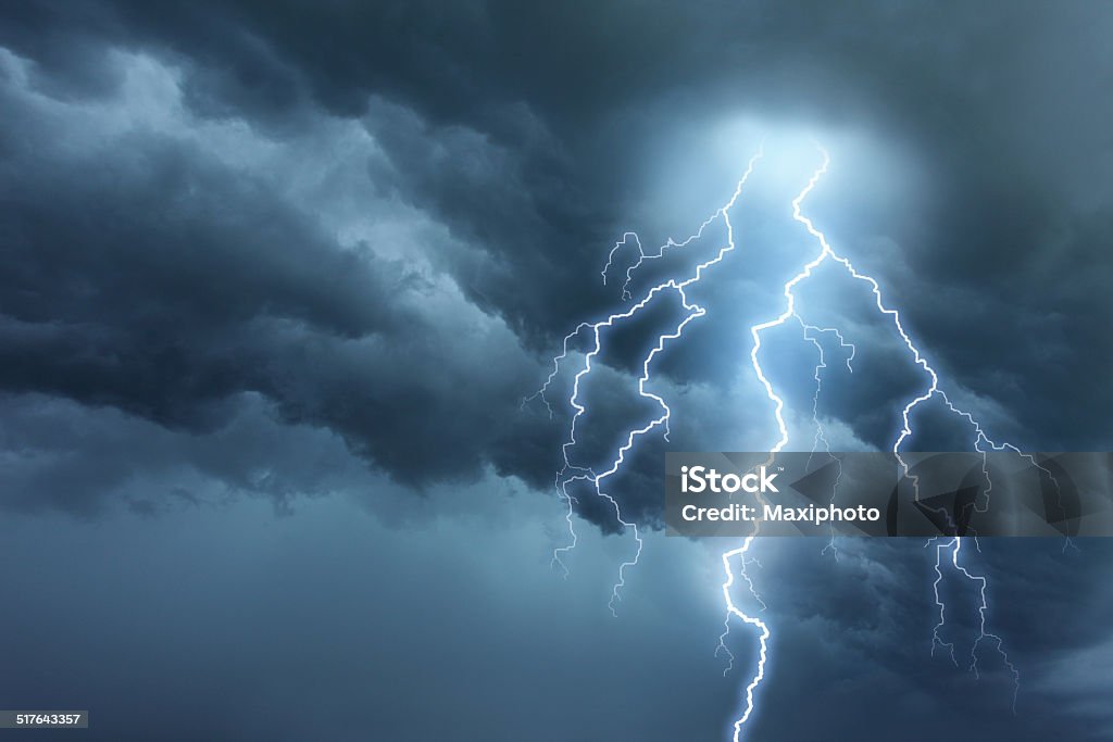 Thunderstorm lightning with dark cloudy sky Bright lightning illuminates dark cloudy sky during a thunderstorm. Natural dangers and majestic beauty. Real cloudscape with computer generated lightning. Copy space on image side. Storm Stock Photo