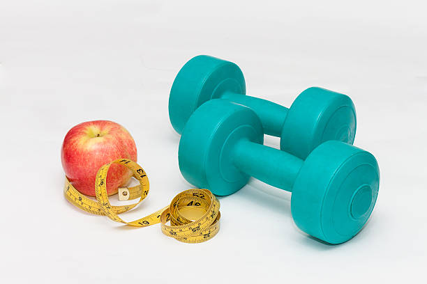 istock Blue dumbbells, red apple, tape on white background 517653332