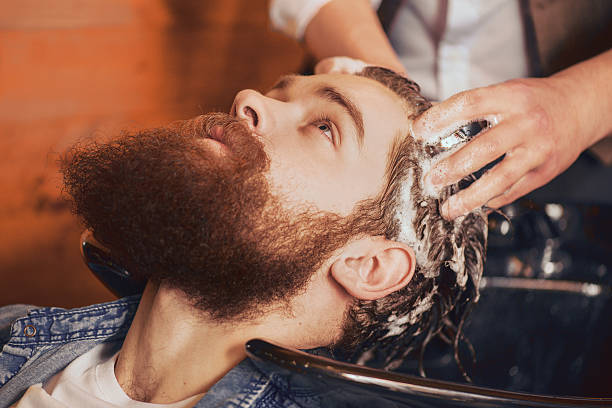 istock professional barber washing head of his client 517654518
