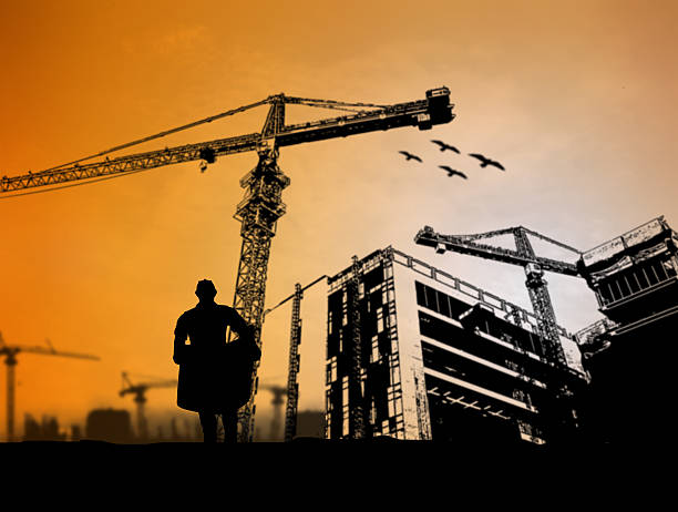 istock silhouette engineer looking at blueprints in a building site ove 517655628
