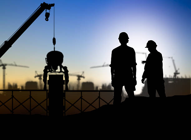 istock silhouette engineer looking at blueprints in a building site ove 517657994