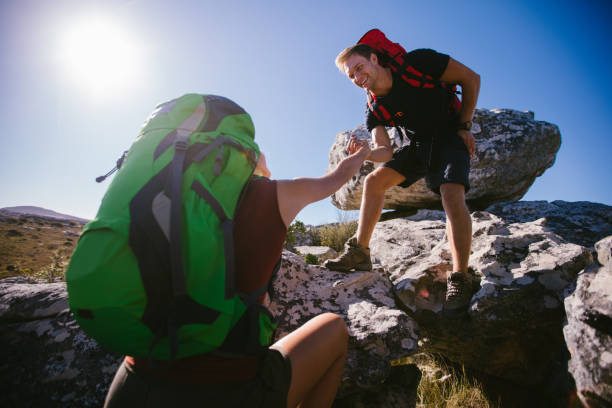 istock Rock climbing couple helping each other hiking over mountain 517658422