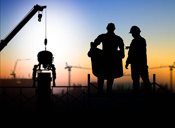 istock silhouette engineer looking at blueprints in a building site ove 517658824
