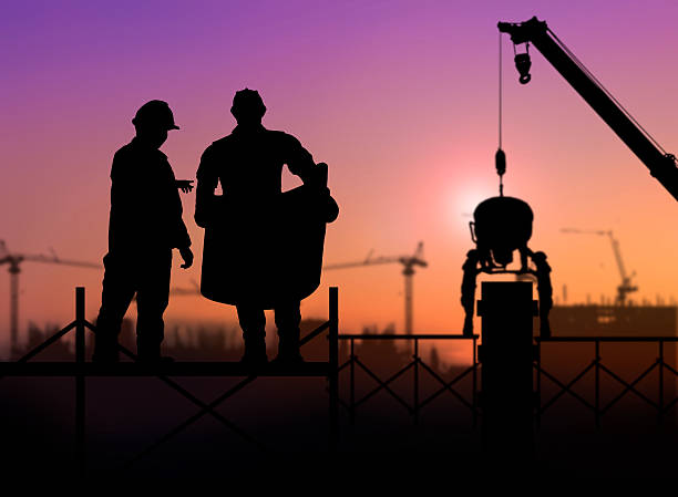 istock silhouette engineer looking at blueprints in a building site ove 517659036