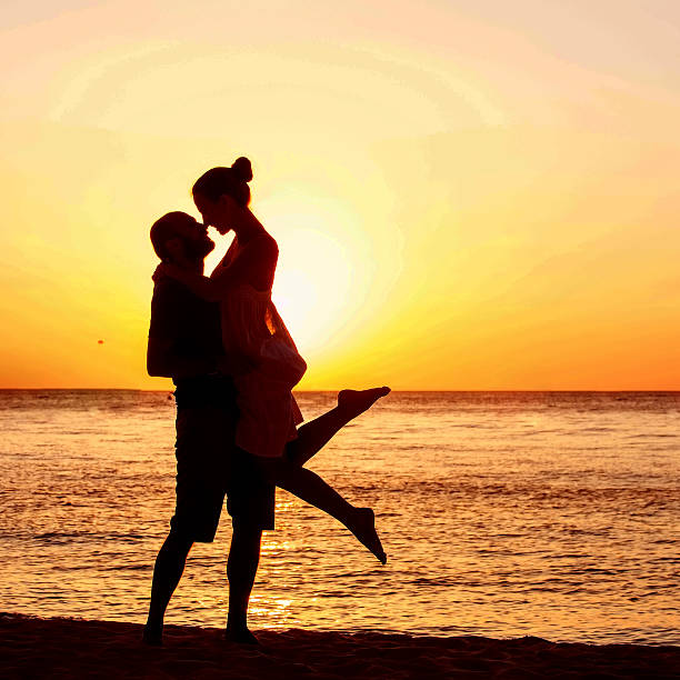 istock Romantic couple on the beach at colorful sunset on background 517660212
