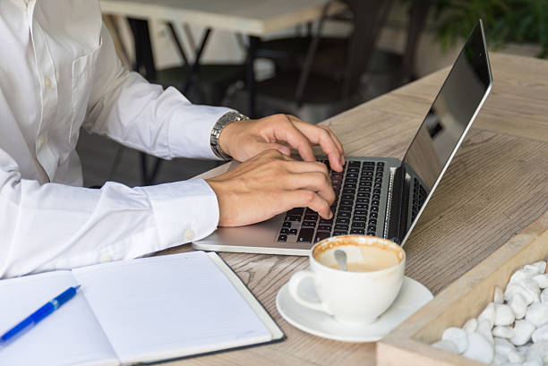Working on laptop with note book and cup of coffee stock photo