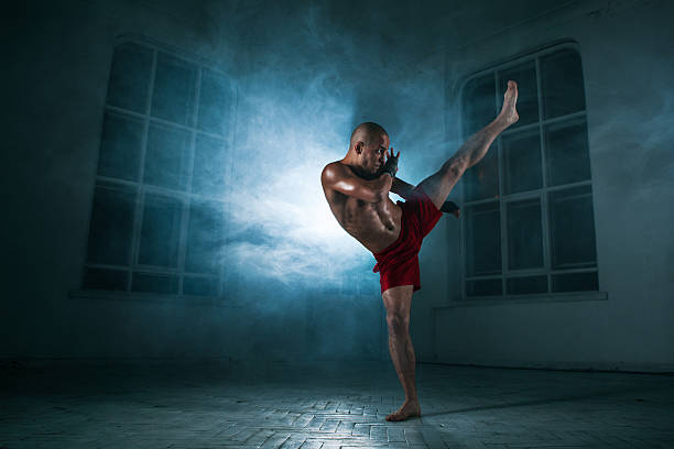 istock The young man kickboxing in blue smoke 517661250