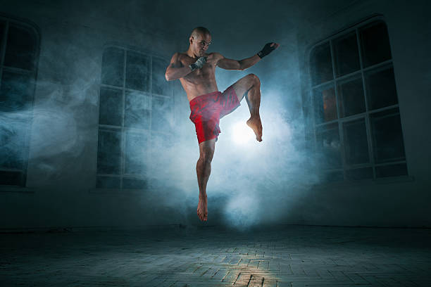 istock The young man kickboxing in blue smoke 517661296