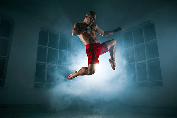 istock The young man kickboxing in blue smoke 517661342