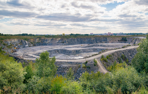 Quarry for gravel extraction on a background of blue clouds