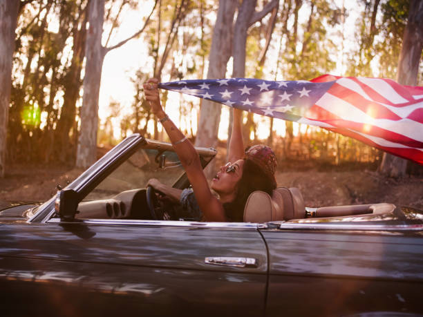 rapariga adolescente segurando uma bandeira americana sobre uma viagem por estrada - driving car drive women imagens e fotografias de stock