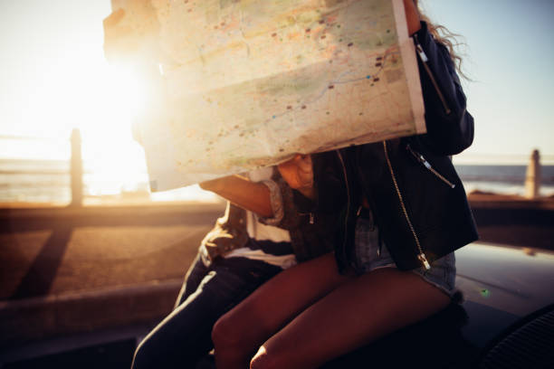 istock Hipster couple looking map on summer road trip with convertible 517665560