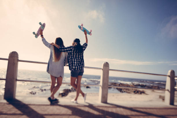 hipster meninas com pranchas de skate em dia de verão na praia - bff imagens e fotografias de stock