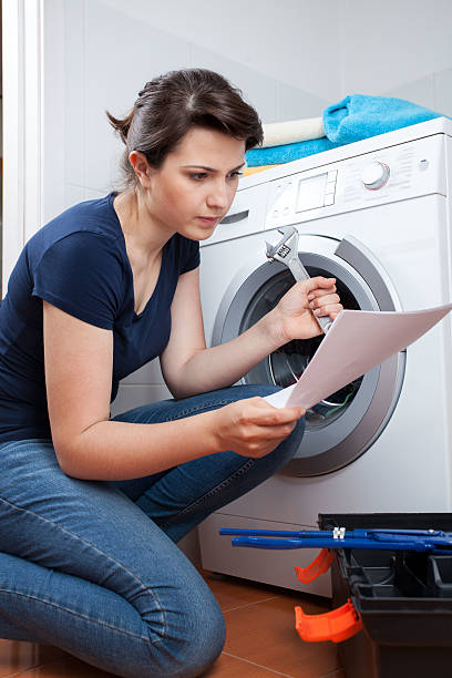 Woman trying to repair washing machine Woman reading manual instruction and trying to repair washing machine adjustable wrench photos stock pictures, royalty-free photos & images