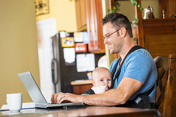 istock Father smiling while taking care of baby and working 517672621