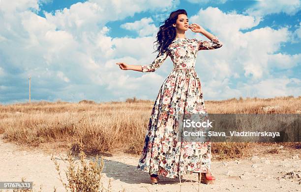 Beautiful Woman In Luxurious Floral Dress Posing In Summer Field Stock Photo - Download Image Now