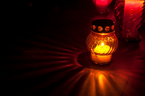 Colorful candle on cemetery in night