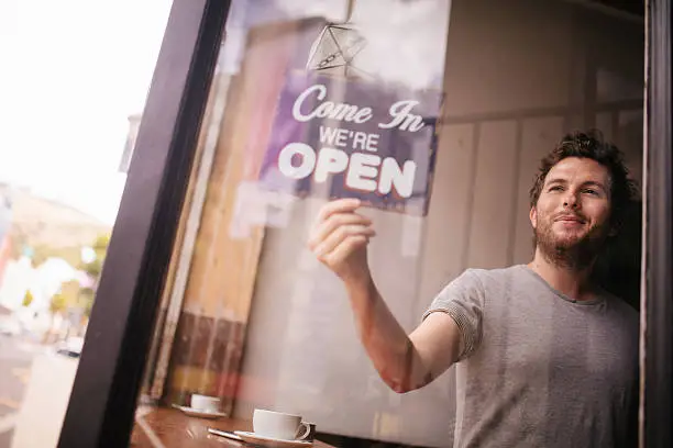 Photo of Hipster Man Turning Opening Sign on Door Coffee Shop