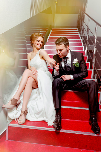 bride and groom on stairs having fun, kissing hand.