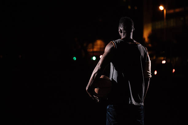 jogador de basquete com bola de basquete no quadril em noite - street light dark street men - fotografias e filmes do acervo