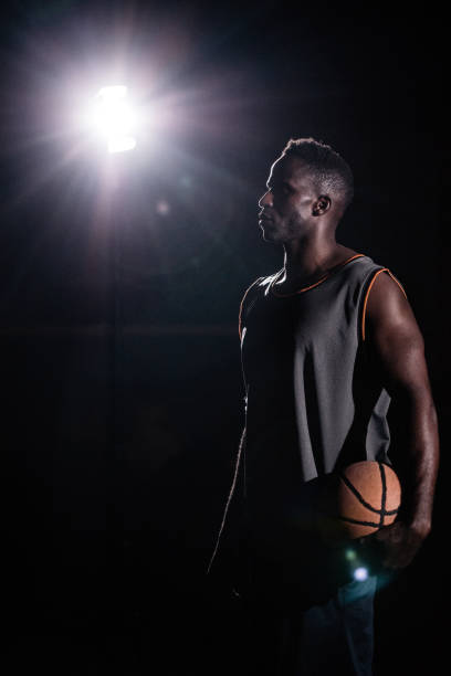 istock Basketball Player Standing Facing Left and Holding Ball in Night 517680276