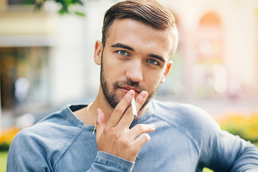 Attractive young male smoking and looking at camera