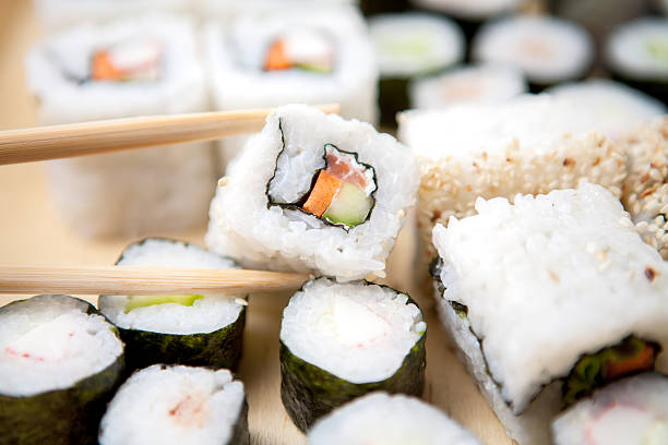 Levantar um pedaço de sushi com Pauzinhos - fotografia de stock