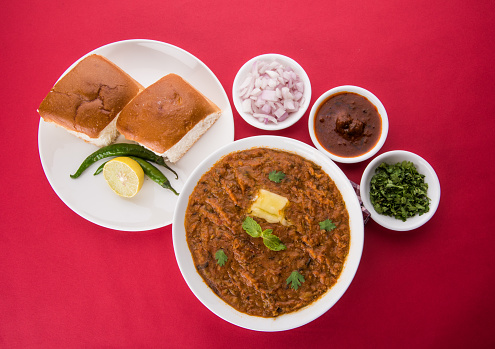 Pav Bhaji Indian spicy fast food with bread, onion and butter. Indian food famous as Mumbai chapati or beach food, served in white ceramic crockery