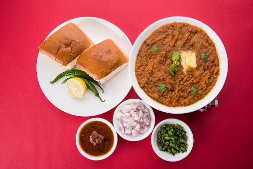Pav Bhaji Indian spicy fast food with bread, onion and butter. Indian food famous as Mumbai chapati or beach food, served in white ceramic crockery