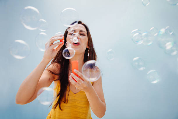 istock Childish mid adult lady blowing bubbles 517690350