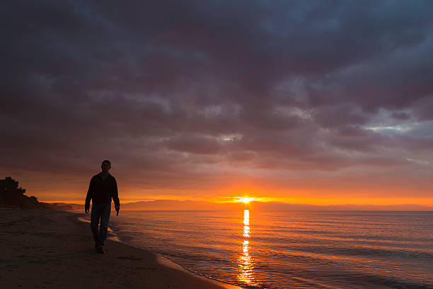 Man walking on beach holding gun stock photo