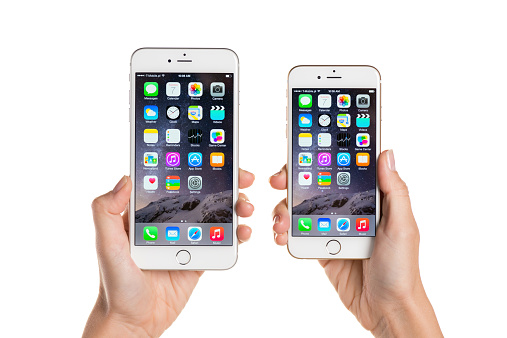Koszalin, Poland - October 07, 2014: Close-up shot of iPhone 6 and iPhone 6 Plus hand-held by woman. iPhone 6 (4.7 inches) and 6 Plus (5.5 inches) are next generation smartphone from Apple. Devices displaying the applications on the home screen.