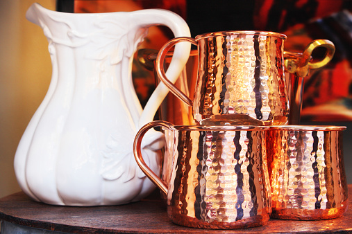 Porcelain china water pitcher and hammered copper cups.
