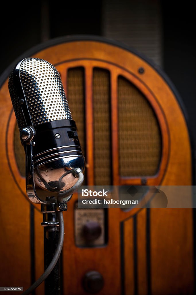 Antique Microphone and Radio A wooden wireless stands behind a shiny microphone, evoking  mid-century radio broadcasting. Radio Stock Photo