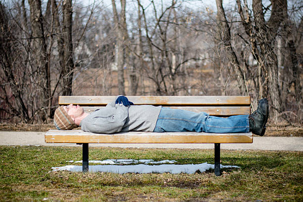 istock Homeless man on a bench sticking out tongue 517701782