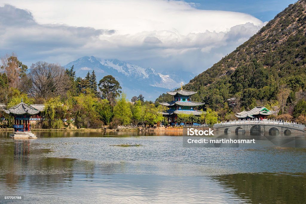 Amazing view of  Jade Dragon Snow Mountain Amazing view of the Jade Dragon Snow Mountain and the Black Dragon Pool, Lijiang, Yunnan province, China. The Suocui Bridge over pond and the Moon Embracing Pavilion in the Jade Spring Park. Black Color Stock Photo
