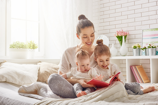 happy loving family. pretty young mother reading a book to her daughters