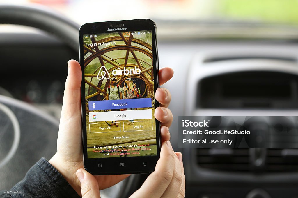 Searching for accomodation Novi Sad, Serbia - March 24, 2016: Close-up of an unrecognizable woman using the Airbnb App on her Lenovo A916 Android smartphone in a car. Login screen with Facebook and Google sign up options. Airbnb is a service for people to list, find, and rent lodging. It currently has over 1,500,000 listings in 34,000 cities and 190 countries. Airbnb Stock Photo