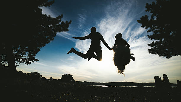 istock groom and bride jumping against the beautiful sky 517704142