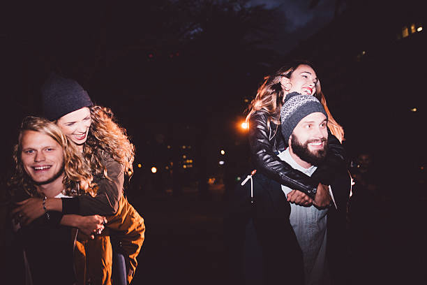 istock Happy young hipster couples having piggyback rides at night 517705840