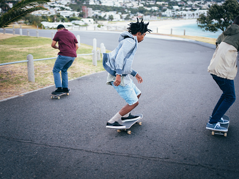 Multi-Ethnic Group of Skaters Skating Down Street at Beach
