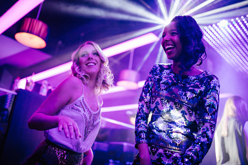 Two happy teenager friends having fun together while dancing at the night club