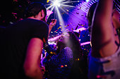 Young friends having fun with confetti on night club party
