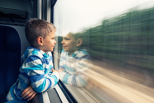 Little boy aged 6 travelling in train. He is smiling and looking out of the window.