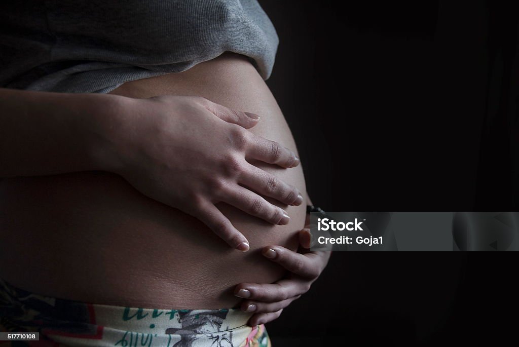 Pregnant woman Pregnant woman cradling unborn child Gestational Surrogacy Stock Photo