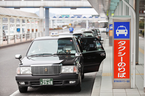 Kagoshima, Japan - January 28, 2012: Taxi cars waiting for passengers at the taxi parking lot in front of the Kagoshima airport building. Kagoshima airport building has both domestic and international terminals
