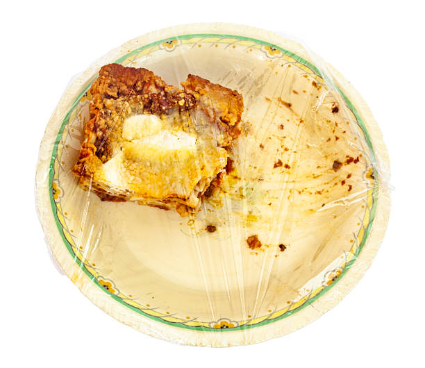 Leftover Lasagna Wrapped in Plastic on a Messy Plate