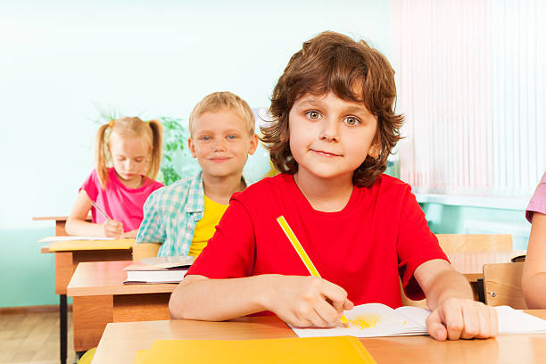 istock Cute boy looking straight and writing with pen 517711669