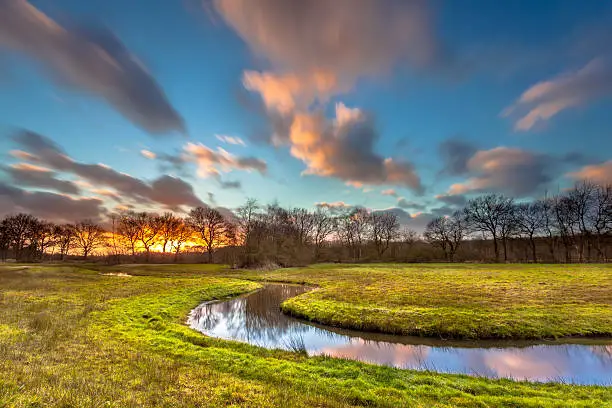 Orange Sunset over Creek with Blurred Clouds by Long Exposure