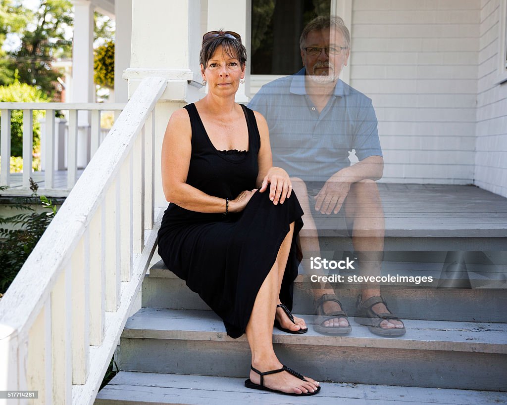 WIdow Woman sitting on the steps of her front porch with husband besides her as a sprit to represent that she is a widow. Front Porch Stock Photo